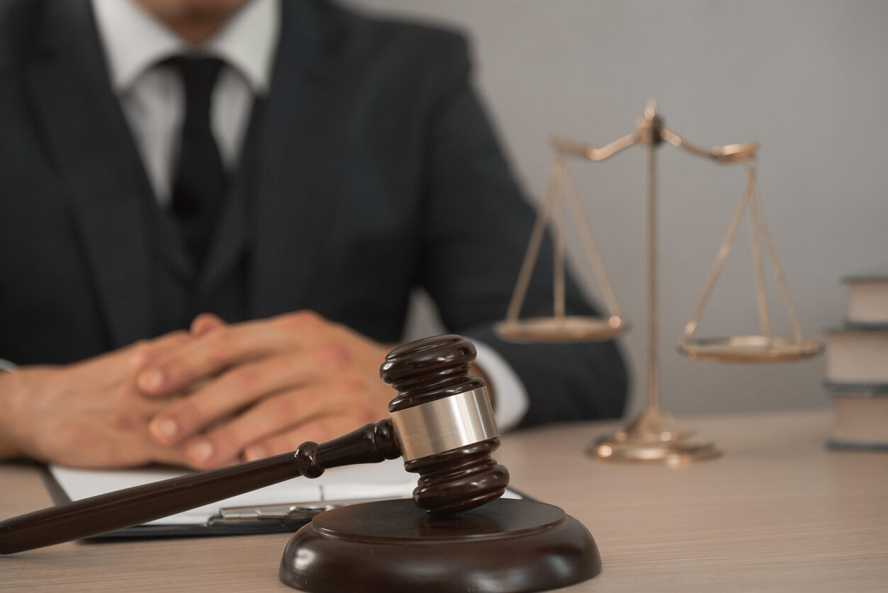 A lawyer in a suit , finger crossed and legal documents at a desk with a gavel, scales of justice, representing a San Diego airplane accident lawyer.