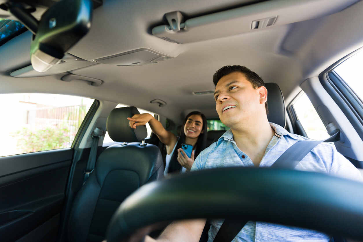 Rideshare driver and passenger inside a car, smiling and enjoying their ride, showcasing the experience of using rideshare services.